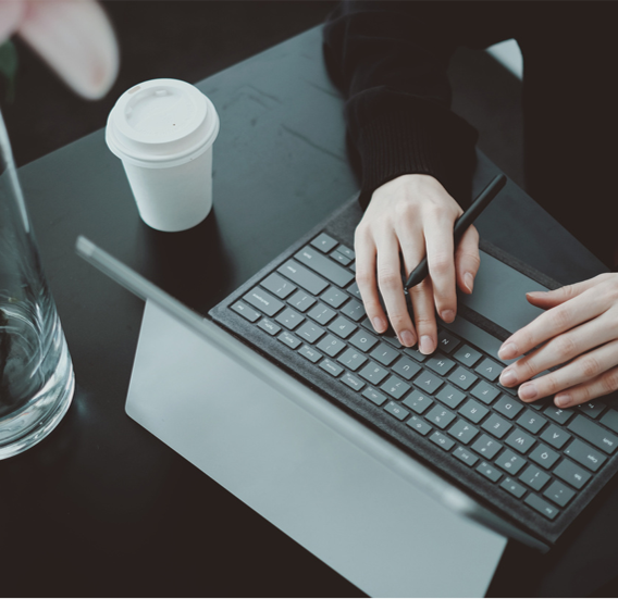 Person typing on a keyboard with a coffee cup nearby